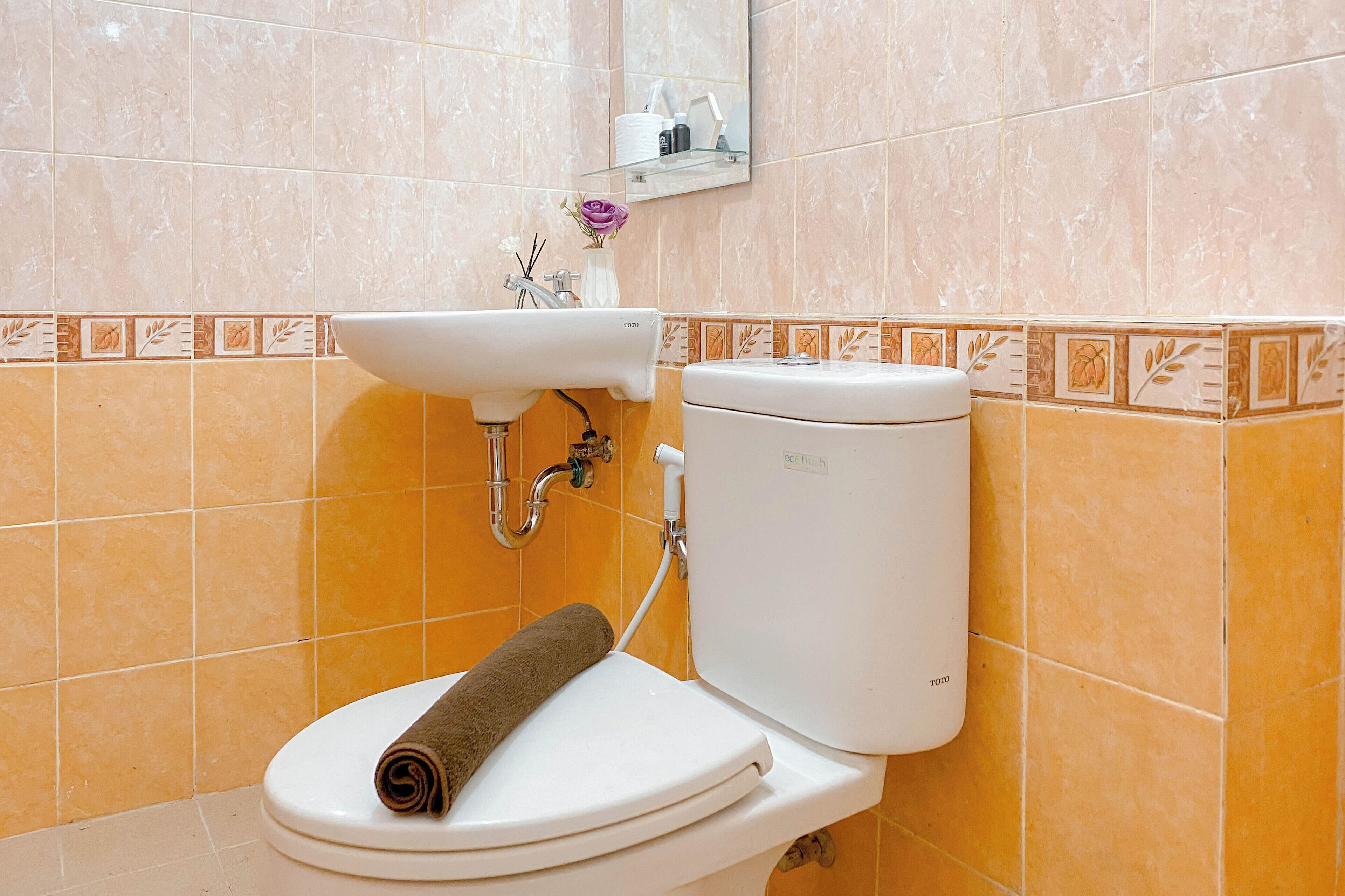 Een badkamer met toilet, wastafel en een handdoek op de zitting.