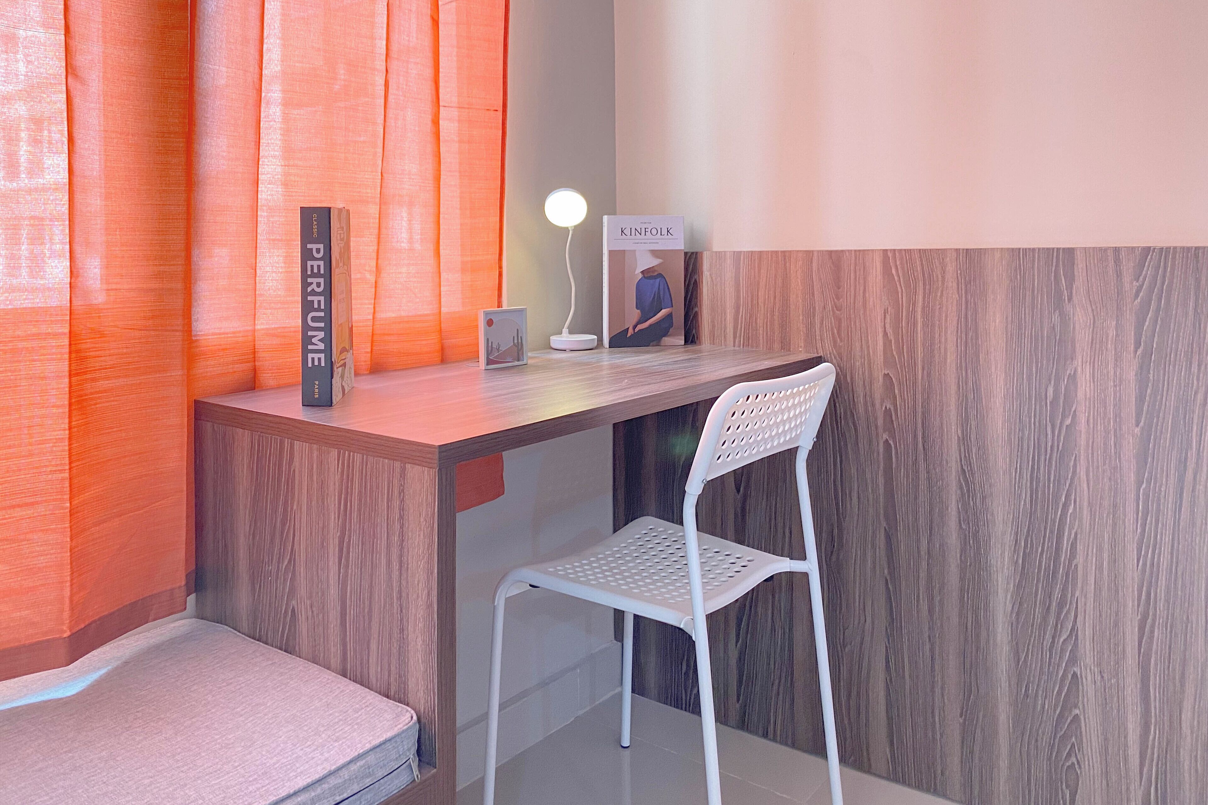 A modern desk with a white chair, a lamp, and a book titled 'KINFOLK'.