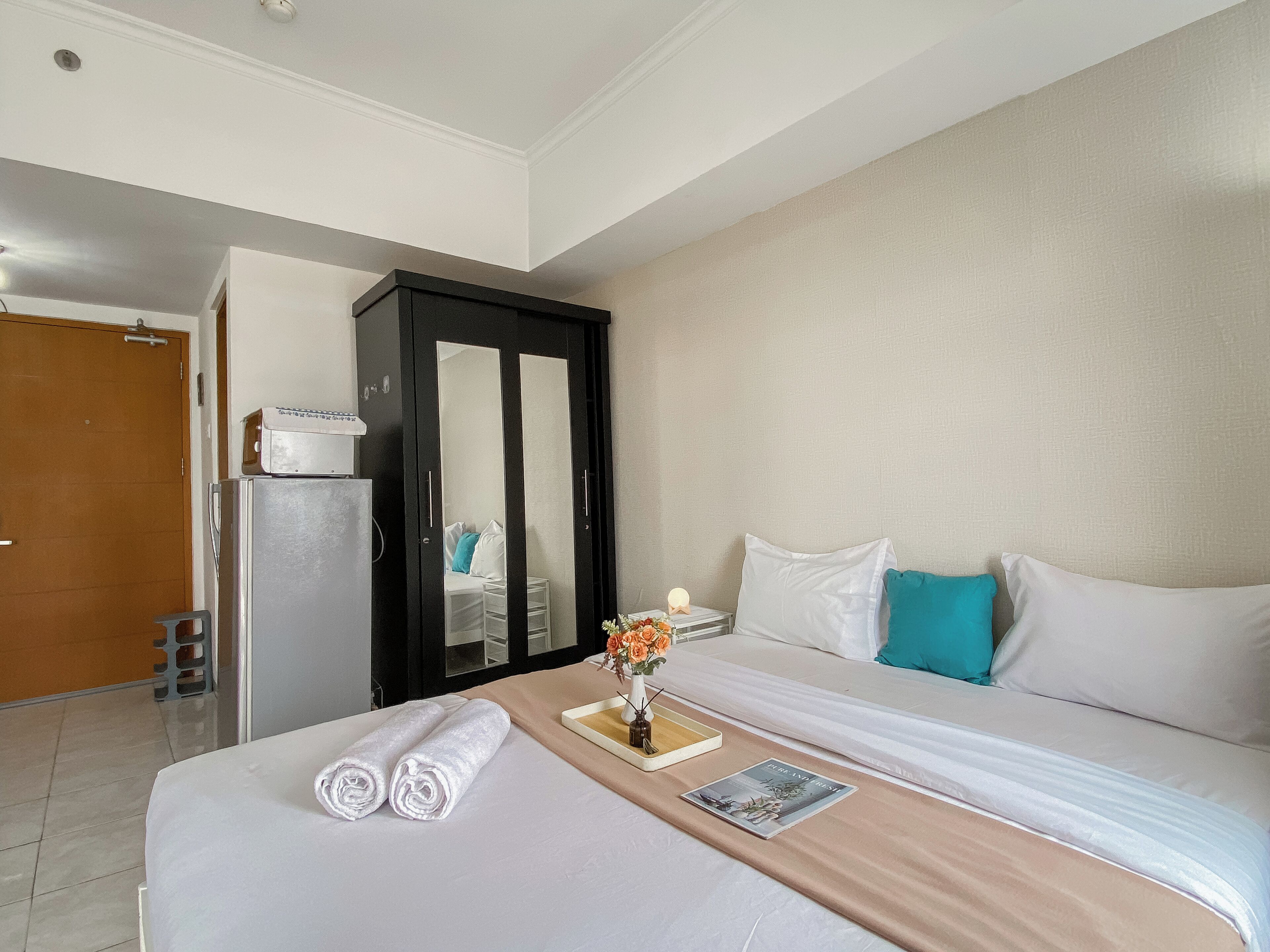 Een hotelkamer met een bed, een dressoir, een spiegel en een nachtkastje met een lamp.