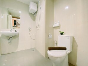 Bathroom features a wall-mounted sink, toilet, and shower area with a showerhead and control panel.