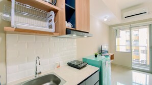 A modern kitchen with a stainless steel sink, wooden cabinets, and a built-in oven. - Cozy Living Studio at LRT City Jatibening Apartment (Bekasi)