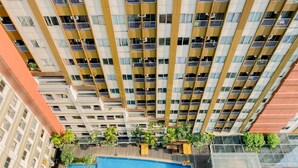 A high-rise building with multiple balconies and a rooftop swimming pool. - Cozy Living Studio at LRT City Jatibening Apartment (Bekasi)