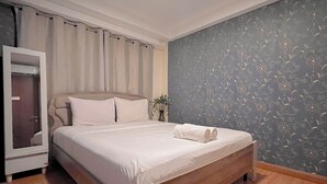 Un lit bien fait, avec du linge de lit blanc, une tête de lit en bois et un mur à motifs sombres.
