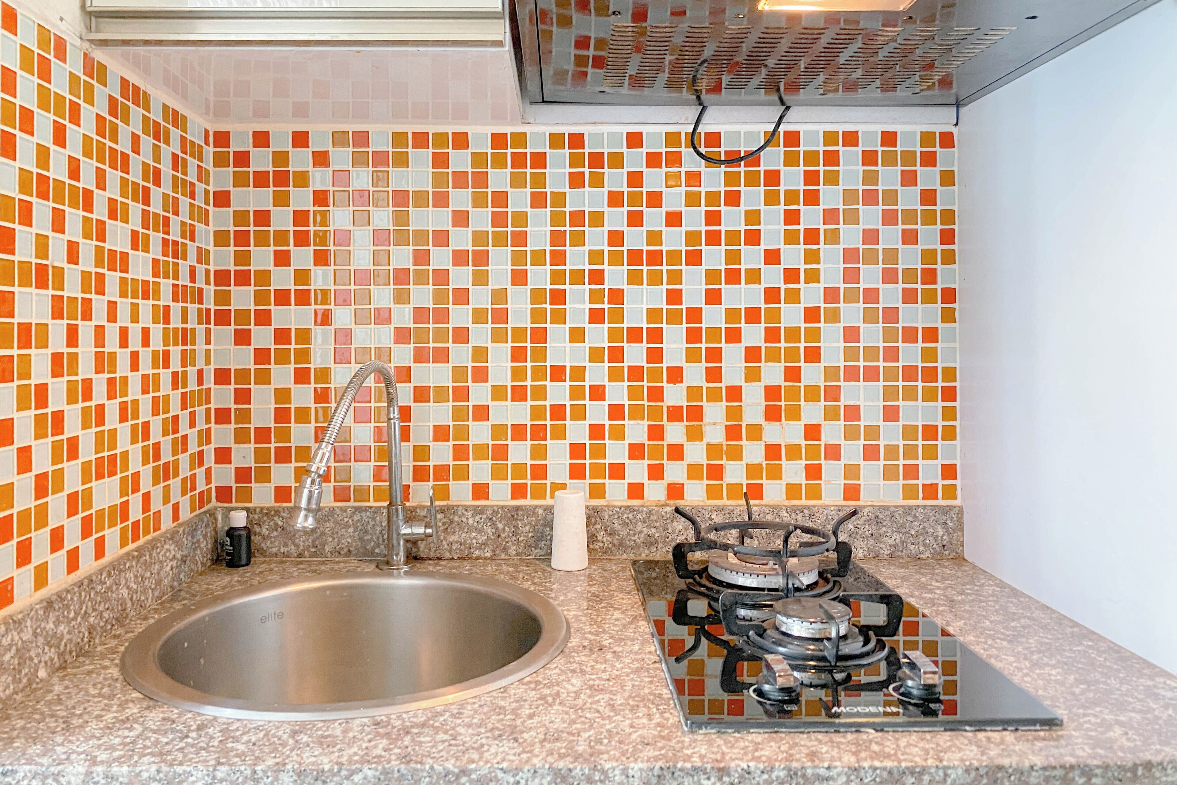 Una cocina con un lavamanos, una estufa a gas y un salpicadero de azulejos.