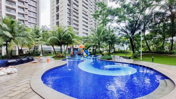 A swimming pool with a spiral design, surrounded by palm trees and a playground.