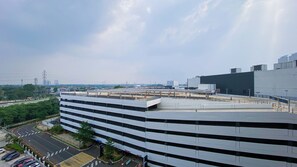 A multi-story building with a flat roof, large windows, and a parking area in front.