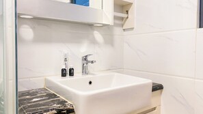 A bathroom with a white sink, a mirror above it, and a marble countertop.