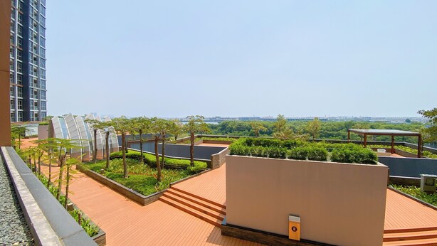 A rooftop terrace with a view of a cityscape, including a modern building and a body of water. - Great Location and Homey Studio Gold Coast Apartment near PIK (Jakarta)