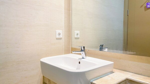 Ein modernes Badezimmer mit einem weißen Waschbecken, einem Chromarmaturen und einem großen Spiegel.