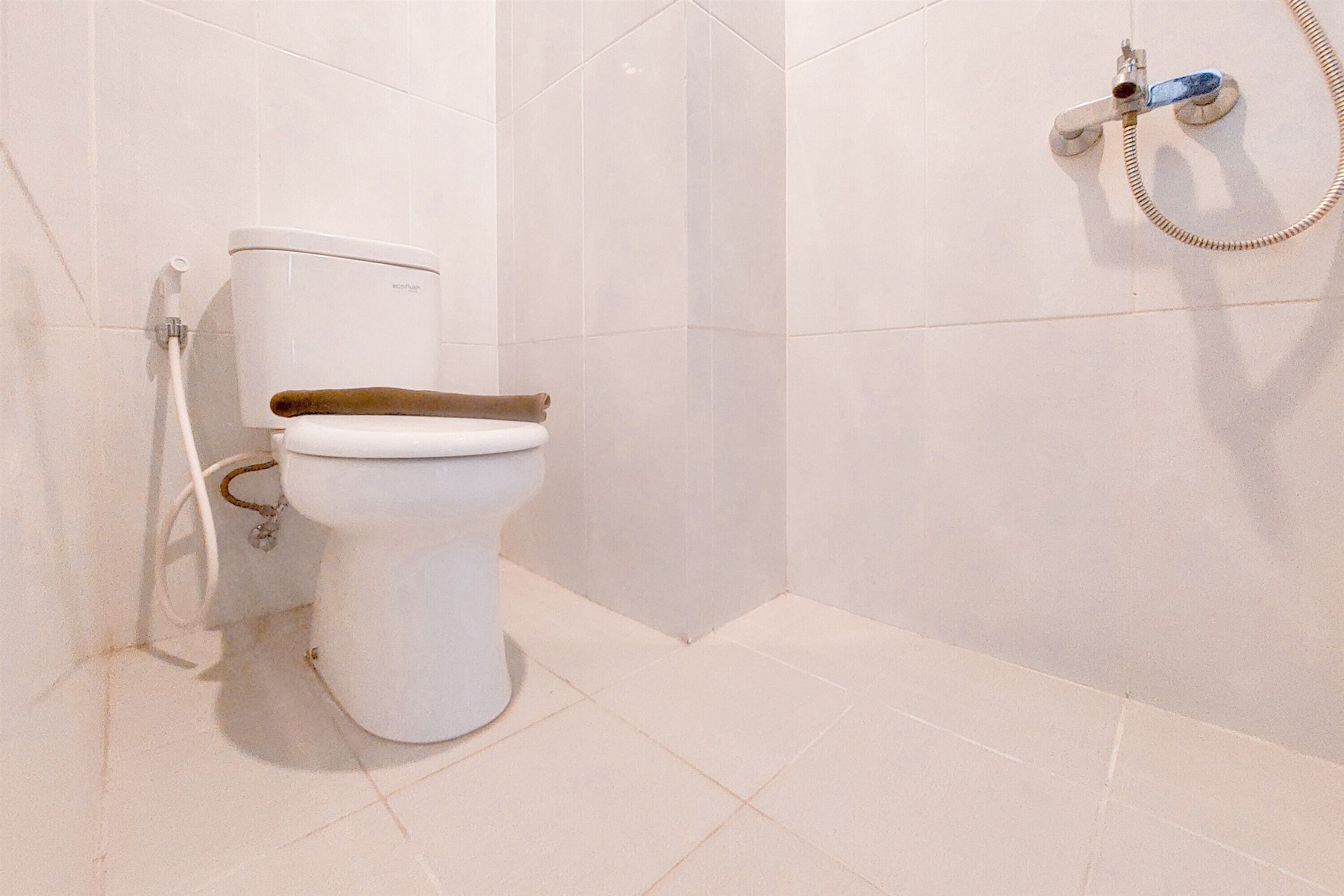 Ein Badezimmer mit Toilette, Dusche und Wandarmatur.