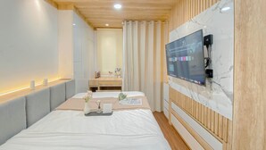 Une chambre d’hôtel moderne dotée d’un grand lit, d’un téléviseur à écran plat fixé sur un mur en marbre et d’un plafond en bois.