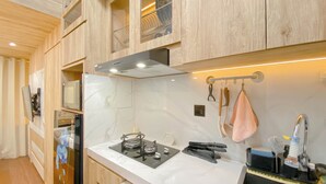 Une cuisine moderne avec des meubles en bois, un plan de travail blanc, un four à micro-ondes encastré et un évier en acier inoxydable.
