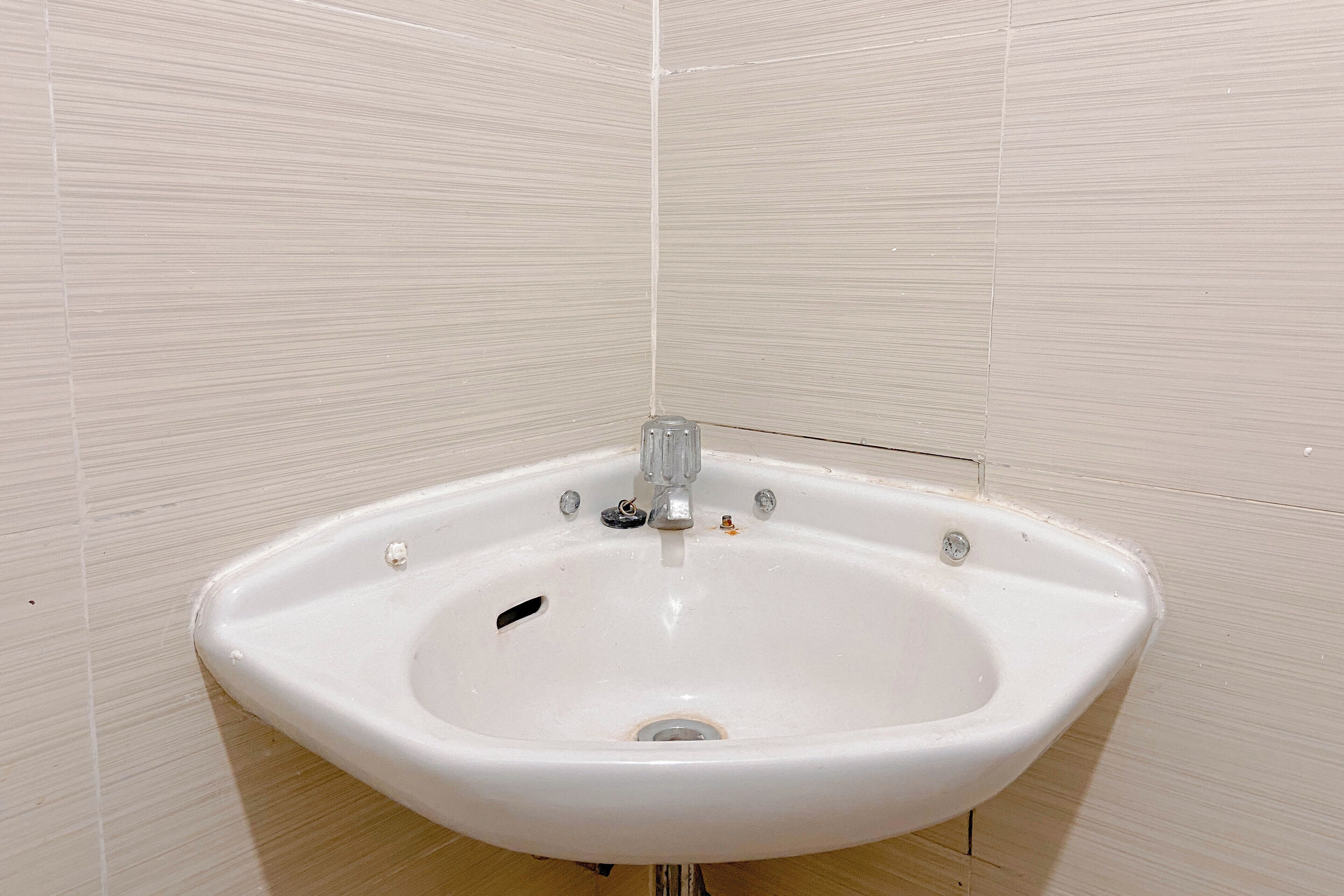A white pedestal sink with a single faucet, set against a tiled wall.