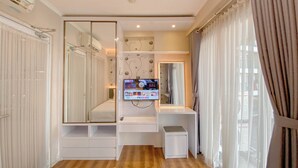 Ein modernes Schlafzimmer mit großem Spiegel, integriertem Fernseher und Schminktisch mit Spiegel.
