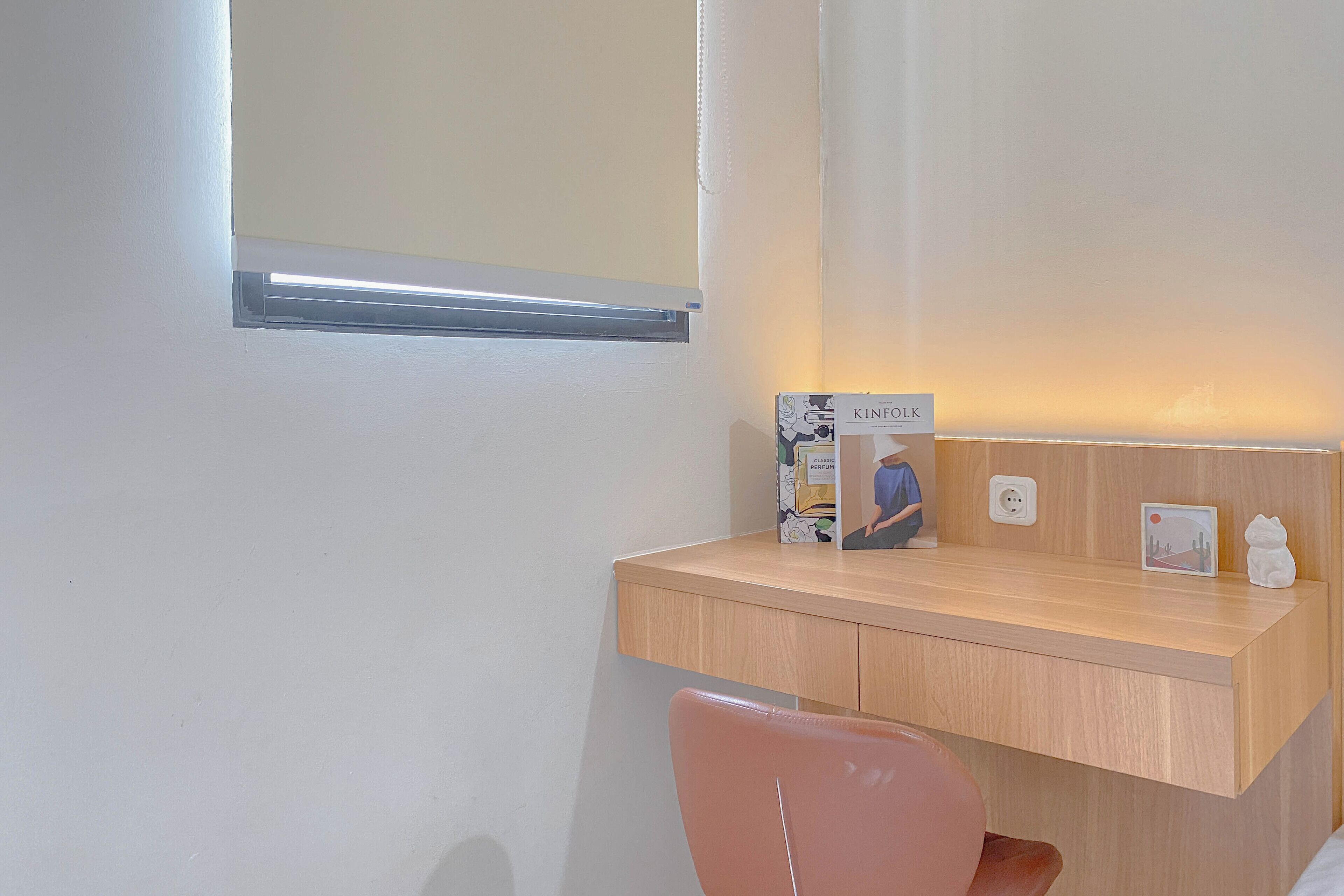 Ein Hotelzimmer mit einem Holztisch, einem kleinen Fenster, einem gerahmten Bild und einem Wanddekor.