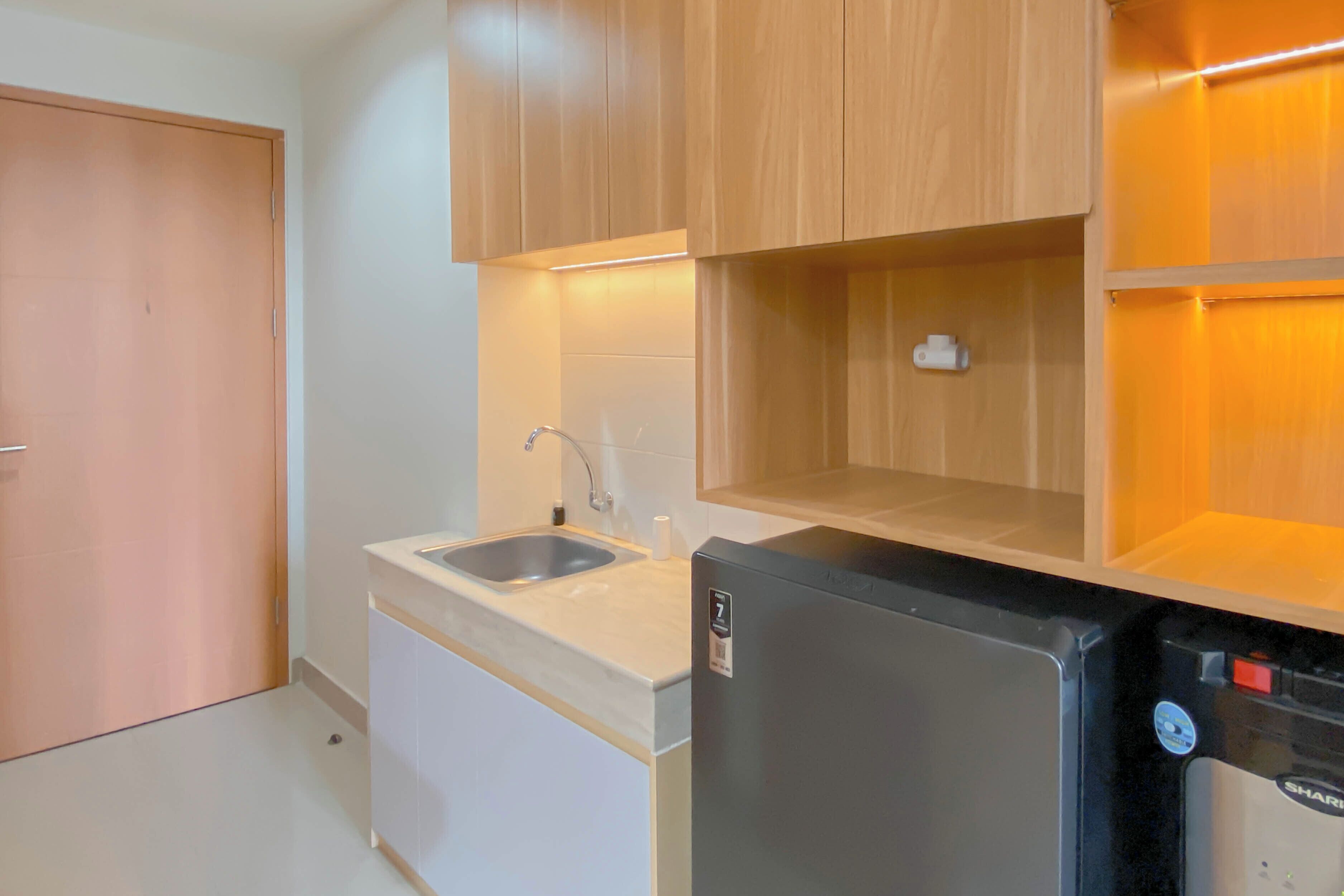 A compact kitchen with wooden cabinets, a sink, and a black refrigerator.