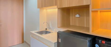 A compact kitchen with wooden cabinets, a sink, and a black refrigerator.