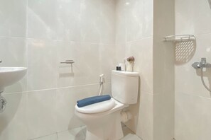 A modern bathroom with a toilet, a sink, and a shower area. - Cozy Living Studio at Evenciio Margonda Apartment (Depok)