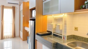 Moderni keittiö, jossa on ruostumattomasta teräksestä valmistettu allas, puukaapit ja sisäänrakennettu mikroaaltouuni.
