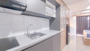 A modern kitchen with a built-in sink, stainless steel faucet, and a range hood. - Good Place and Comfy Studio Apartment Anwa Residence (South Tangerang)
