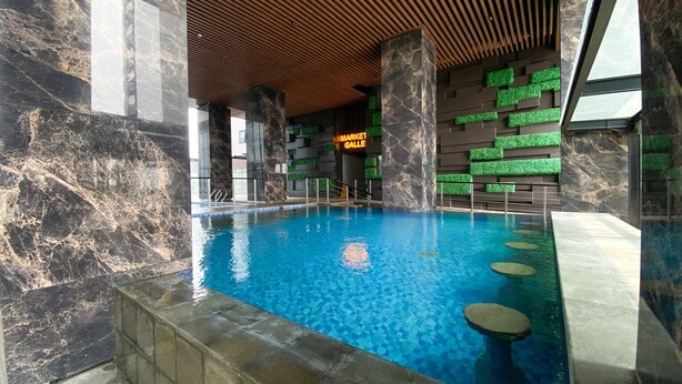 An indoor swimming pool with a wooden ceiling and marble walls, a neon sign reading "MARKET GALLERIES", and a view of the outside through large windows. - Good Place and Comfy Studio Apartment Anwa Residence (South Tangerang)