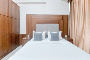 Relax in a stylish room with a made bed, nightstand, and wardrobe.