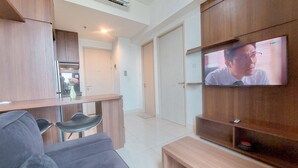 Ein modernes Wohnzimmer mit grauem Sofa, Couchtisch aus Holz und einem an der Wand befestigten Fernseher.