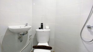 A small, white-tiled bathroom with a sink, toilet, and shower. - Minimalistic and Cozy Studio Amartha View Apartment (Semarang)