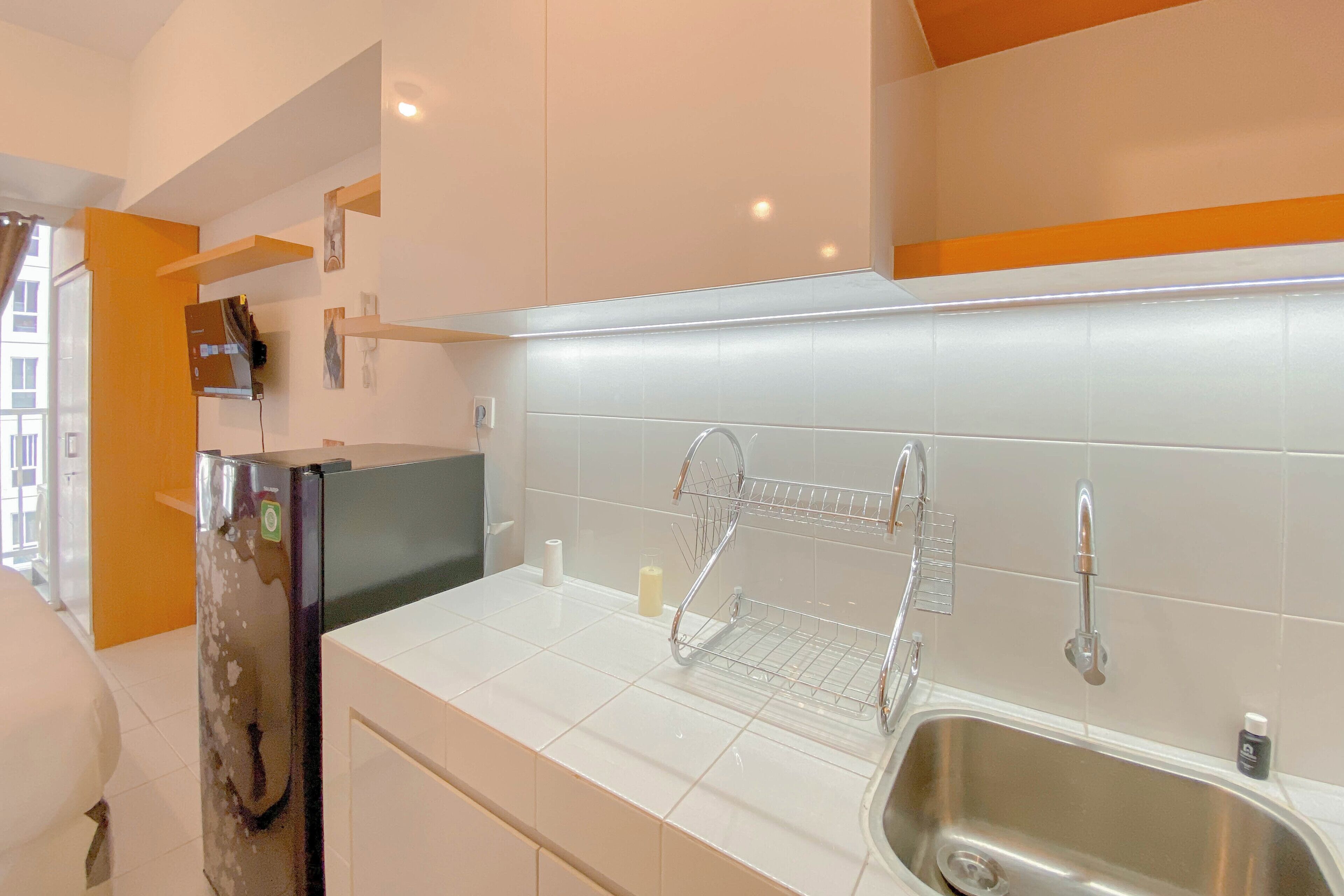 A modern kitchen with white tiles, stainless steel appliances, and a built-in sink.