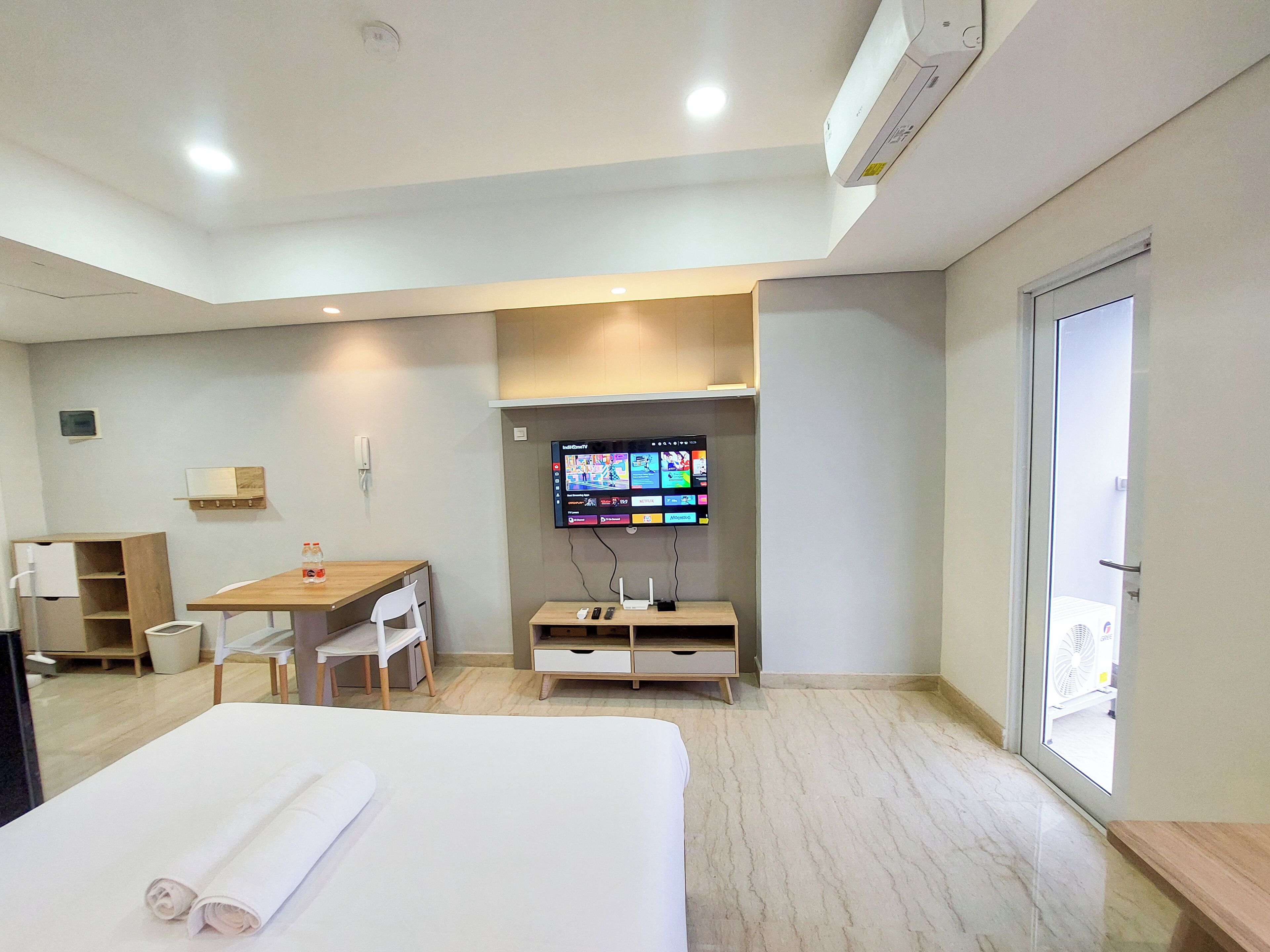 A hotel room with a bed, a desk, a chair, a TV, and a window.