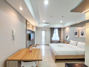 Une chambre d’hôtel avec un lit, un bureau et une chaise, une télévision et une fenêtre avec des rideaux.