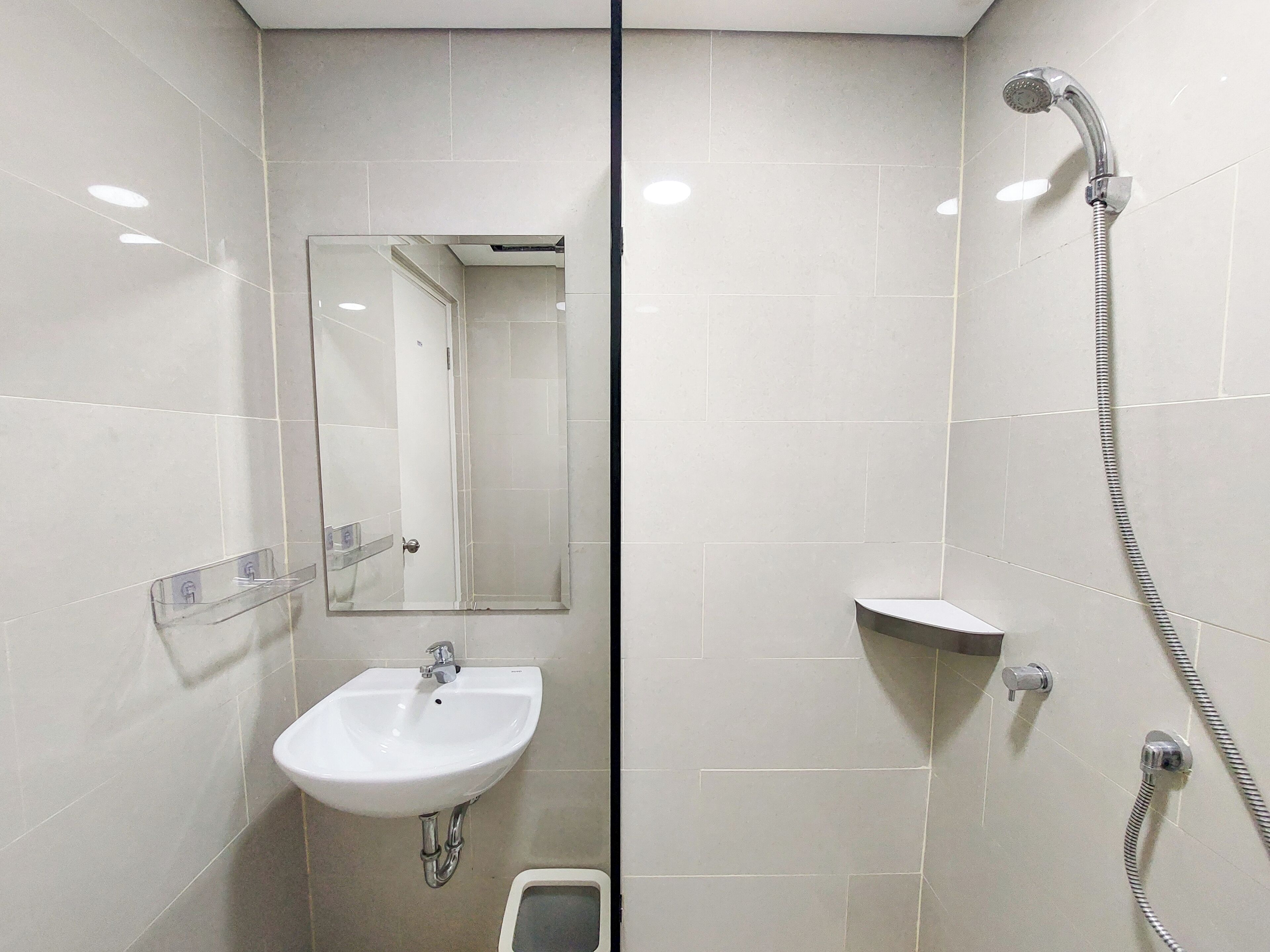 Een badkamer met een wit wastafelmeubel, een spiegel, een douche en een toilet.