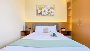 Hotelkamer met een bed, nachtkastje, wanddecoratie en een kledingkast.