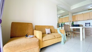 A living room with a sofa, a dining table with chairs, and a kitchen area in the background. - Comfortable and Restful 2BR at Great Western Apartment (Tangerang)