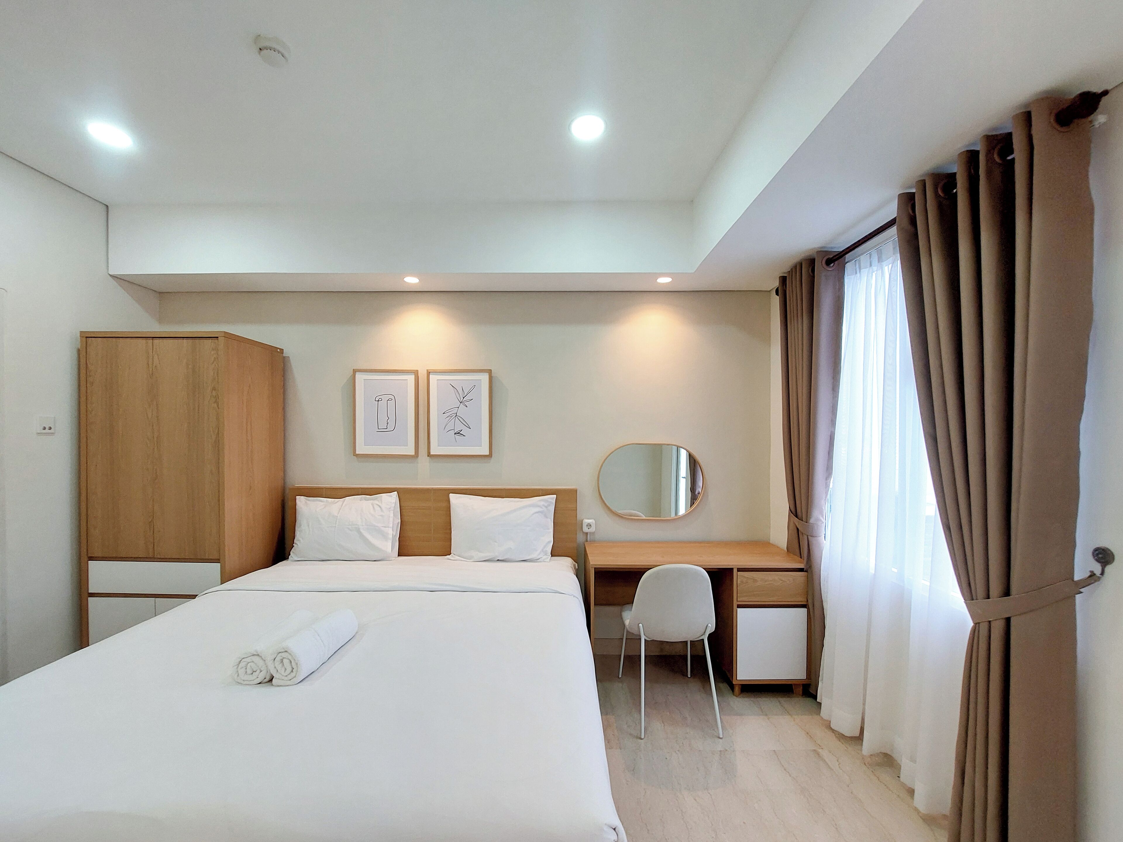 A hotel room with a bed, a desk, a wardrobe, and a mirror.