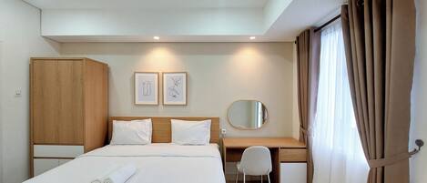 A hotel room with a bed, a desk, a wardrobe, and a mirror.