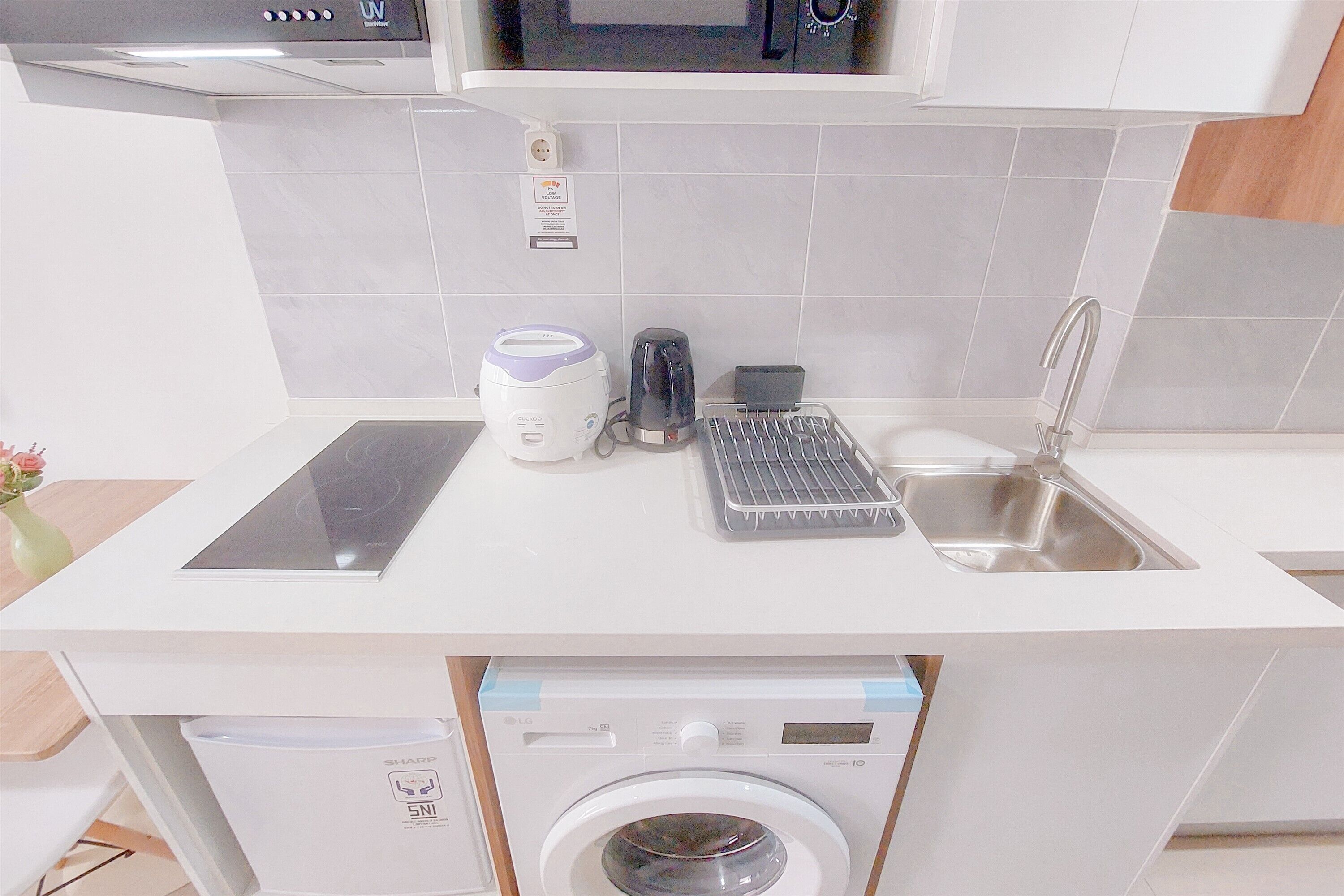 A kitchen with a microwave, toaster, kettle, and sink.