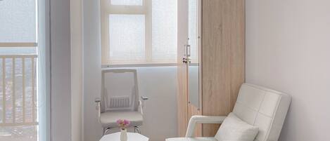 A modern bathroom with a white bathtub, a white chair, and a wooden door.