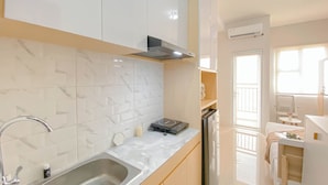 A modern kitchen with a stainless steel sink, a built-in stove, and a compact refrigerator.