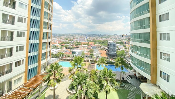 Un hôtel de grande hauteur doté de nombreux balcons, d’une piscine et offrant une vue sur un paysage urbain avec des montagnes à l’horizon.