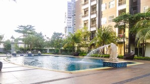 A swimming pool with a water feature, surrounded by greenery and modern buildings. - Modern Look 1BR Apartment at Silkwood Residence (Tangerang)