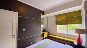 A modern bedroom with a bed, a bench, a desk, and a window with a view. - Modern Look 1BR Apartment at Silkwood Residence (Tangerang)