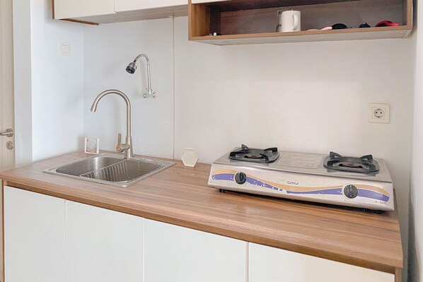 A kitchen with a sink, faucet, and a portable gas stove.