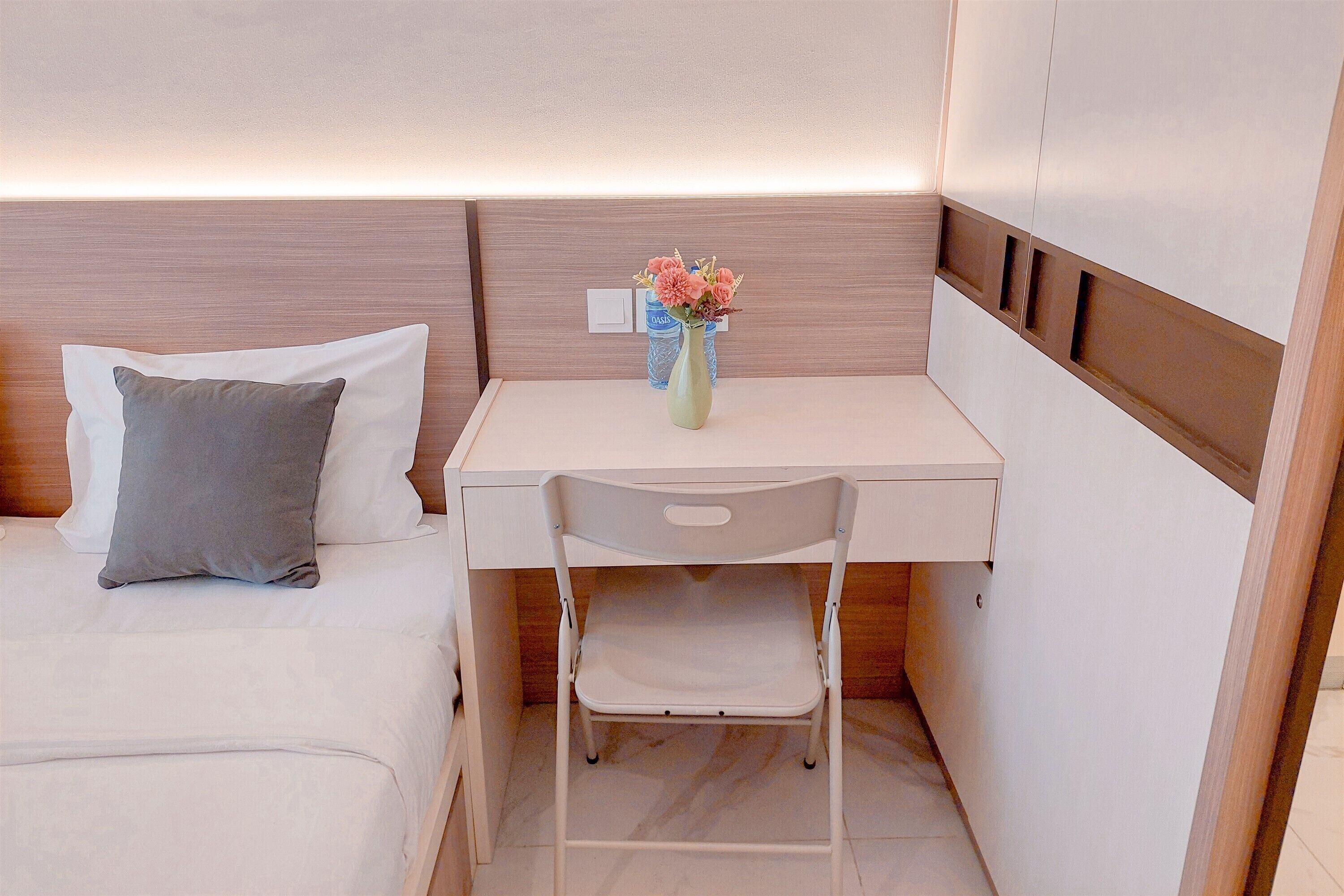 A compact bedroom with a bed, a small desk, and a chair.