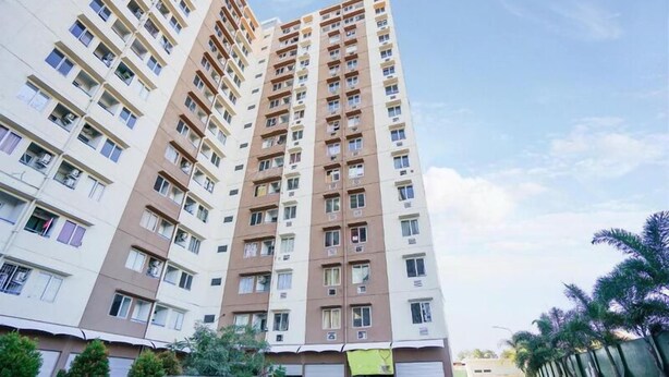 Un edificio residencial alto con múltiples balcones, fachada plana y cielo despejado.