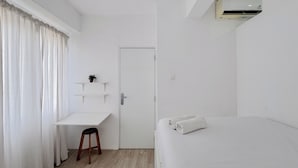Una habitación minimalista con una cama, un escritorio y una puerta.