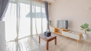 Un salon moderne avec une table basse en bois, un téléviseur posé sur un meuble en bois et une plante en pot.
