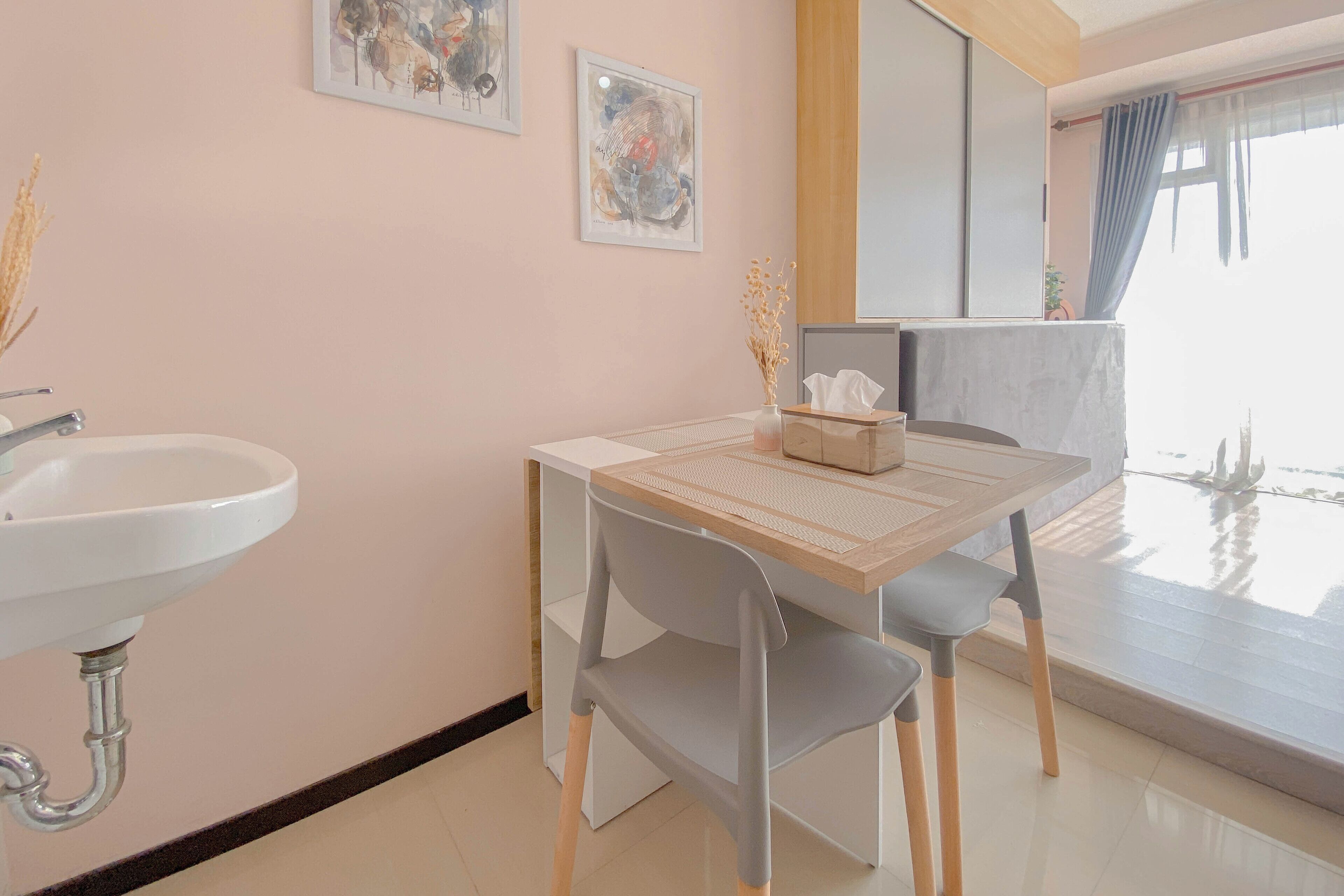 Een moderne badkamer met een wastafel, een houten tafel met stoel, en kunst aan de muur.