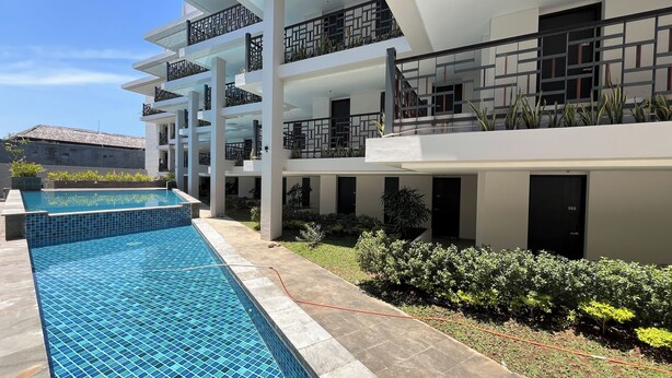 A modern multi-story building with a swimming pool, balconies, and a garden area. - Luxurious 2BR (No Kitchen) Apartment at Skales Residence Nusa Dua Bali (Nusa Dua)