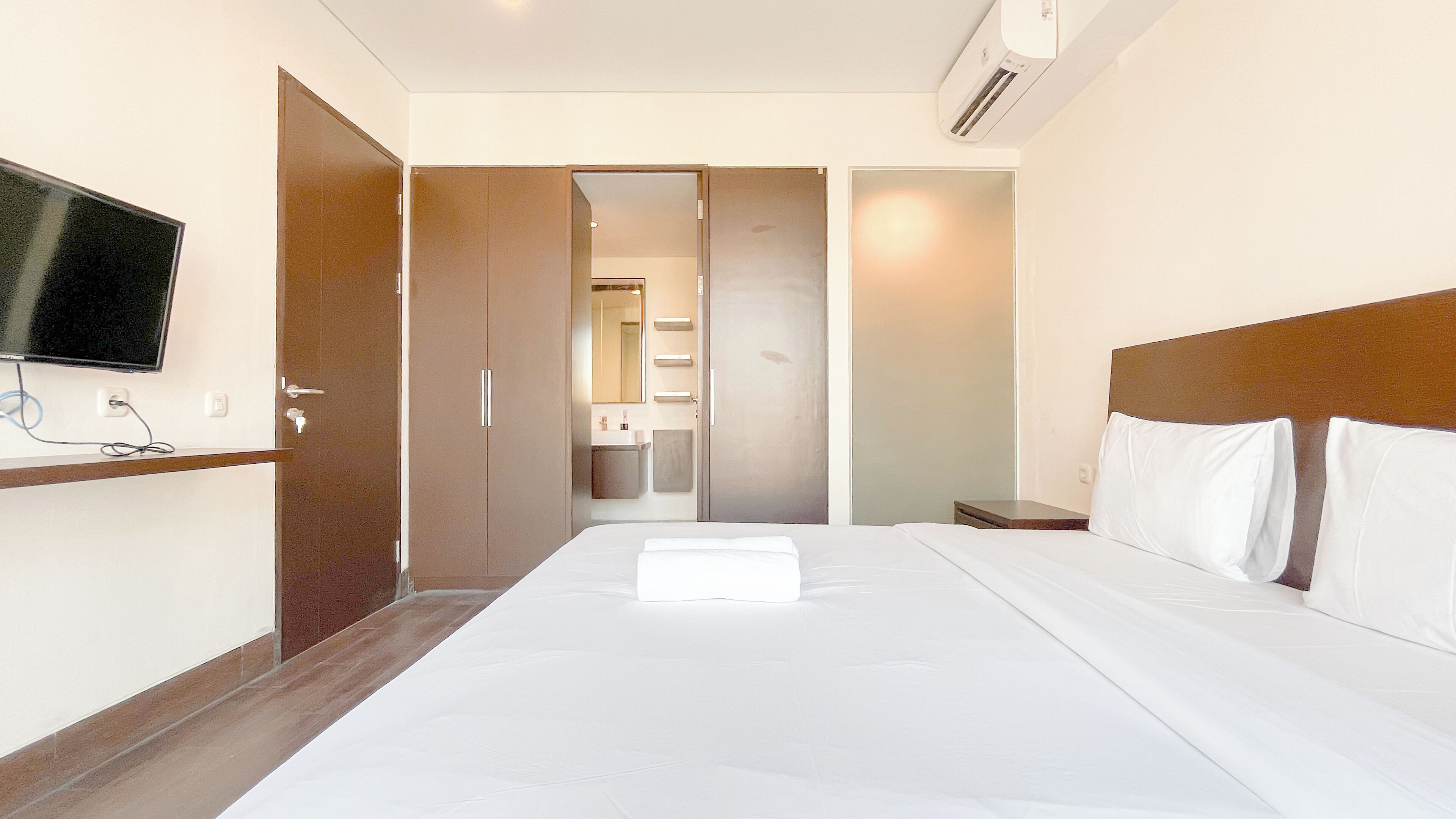 Una habitación de hotel con cama, televisión, baño y armario.